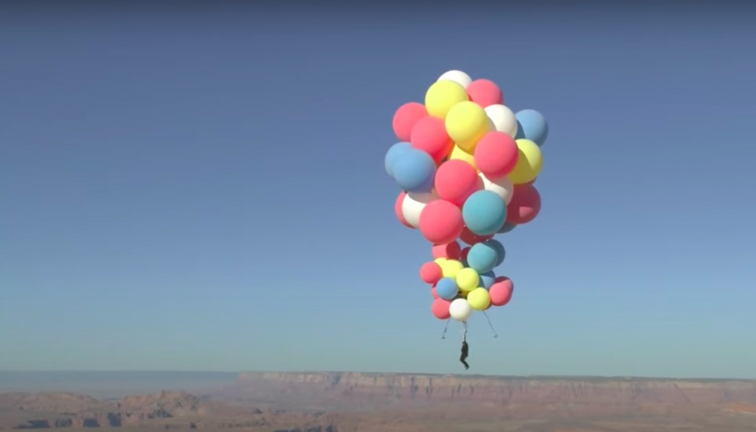 Hombre vuela sobre el desierto, atado a globos de helio