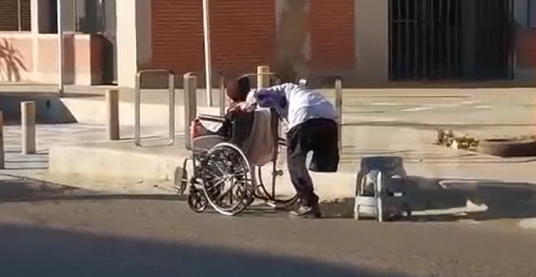 No tiene una pierna y así empuja a su esposa en silla de ruedas